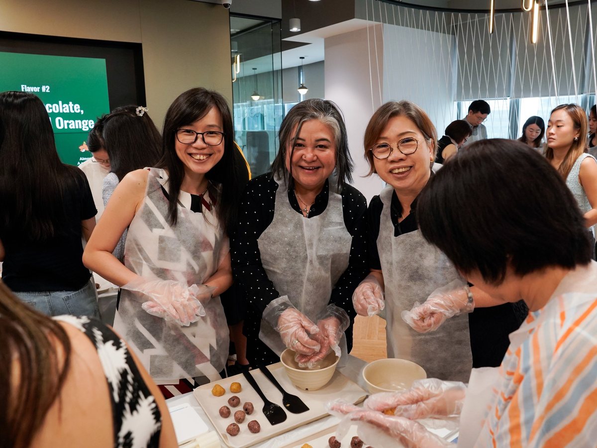 Colleagues laughing while rolling energy balls at a team bonding workshop in Singapore