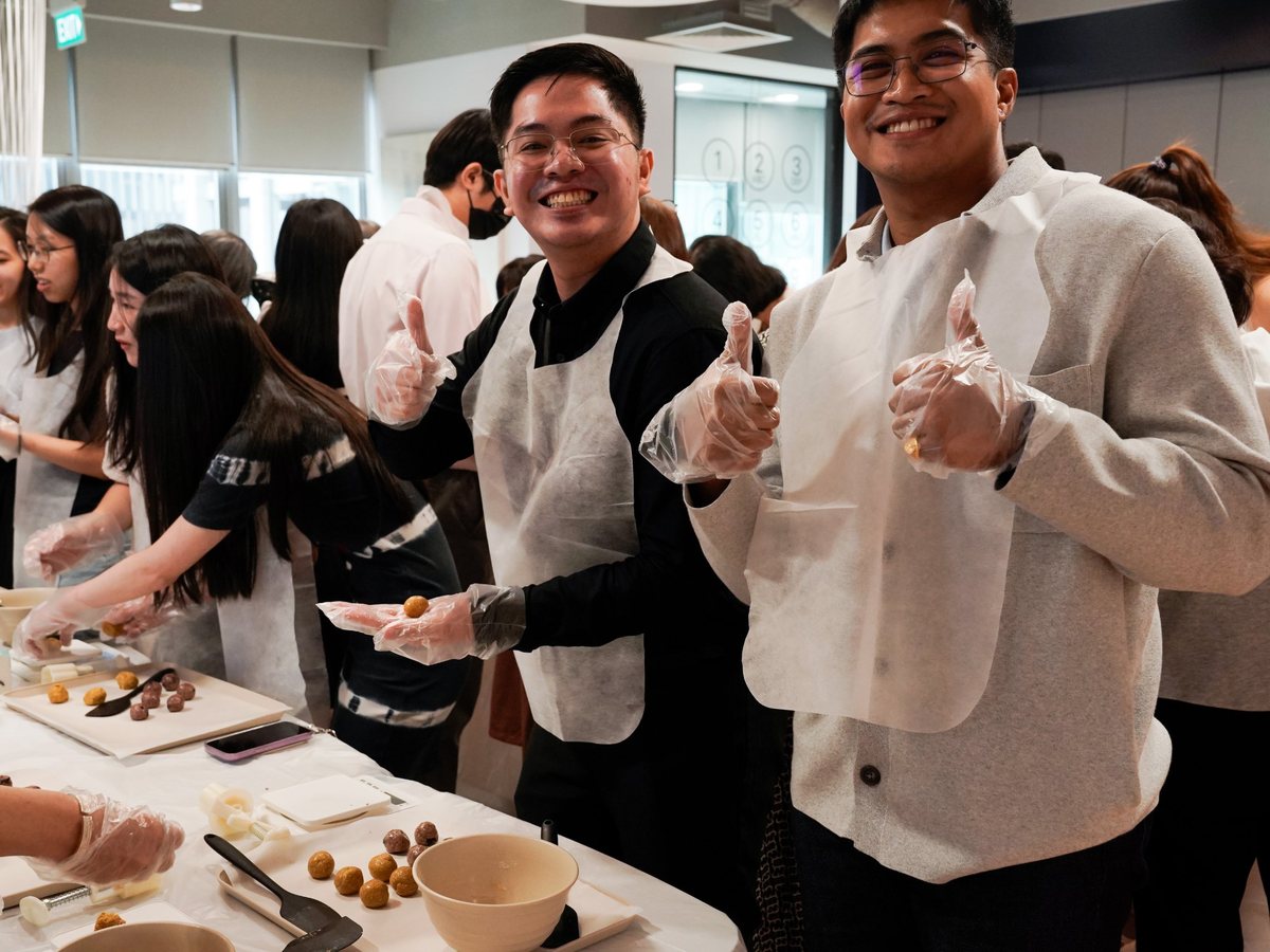 Two colleagues giving thumbs up at a hands-on team building food workshop